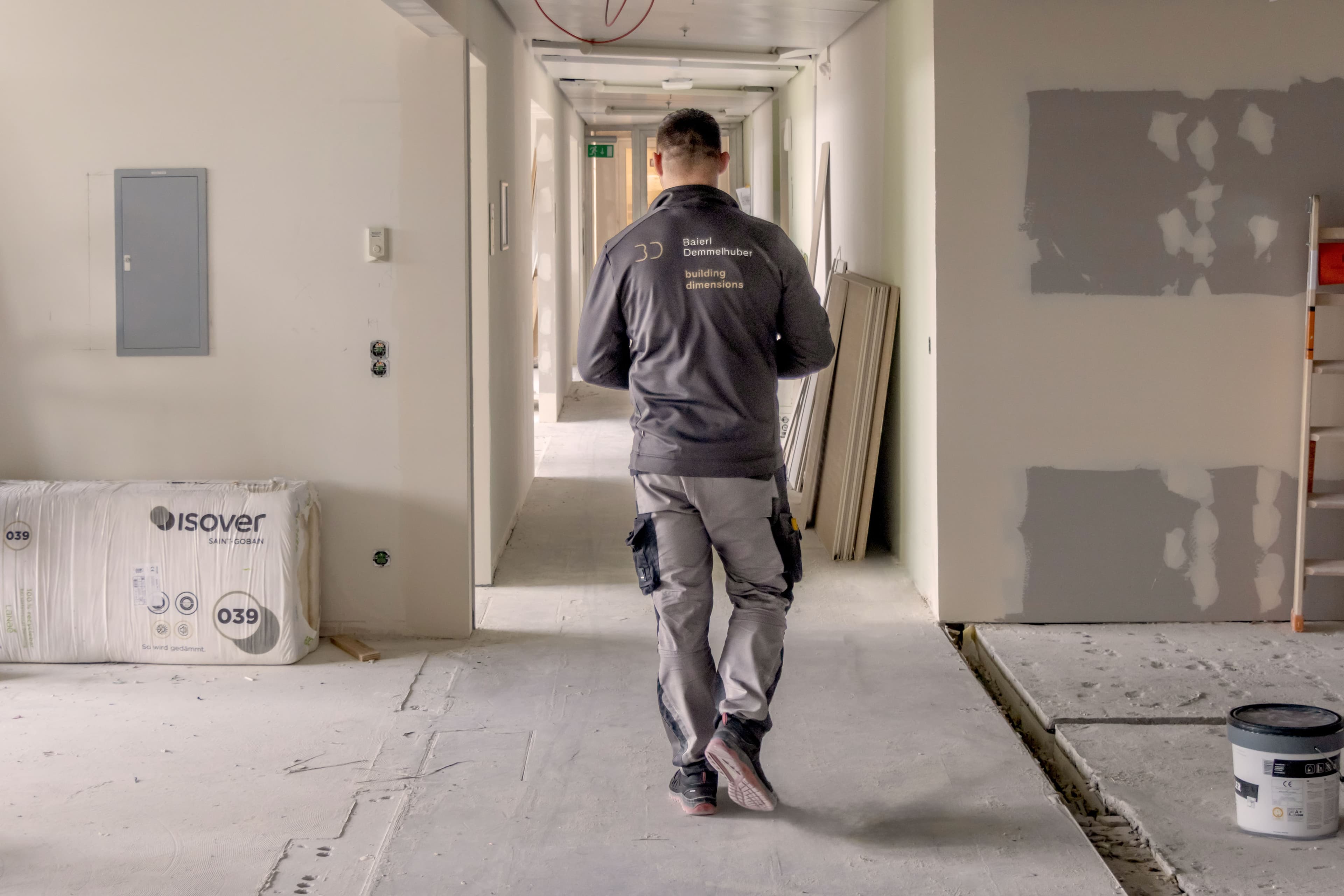 Mitarbeiter von Baierl Demmelhuber geht durch einen unfertigen Flur auf einer Baustelle.
